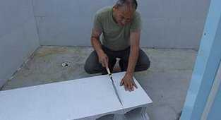 Ein Mann sägt einen Polystyrol Stein in der Länge ab	 