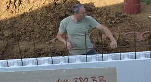 Ein Mann legt einen Eisenstange  in eine Reihe Polystyrolstein ein	